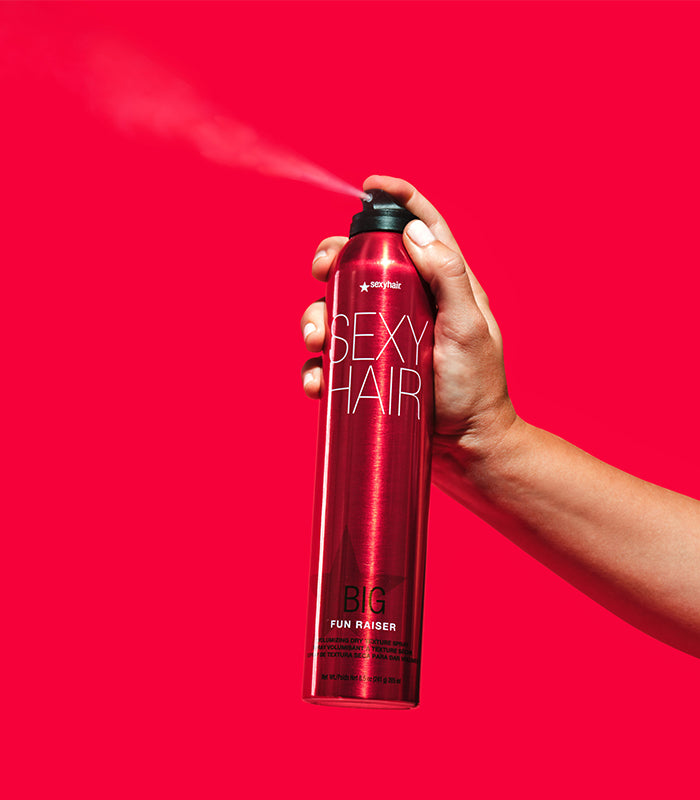 Hand holding Big Fun Raiser spray can on neutral background