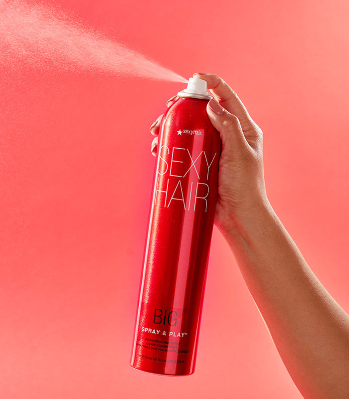 Hand spraying Big Spray & Play hairspray with visible spray mist