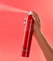 Hand spraying Big Spray & Stay hairspray with visible mist