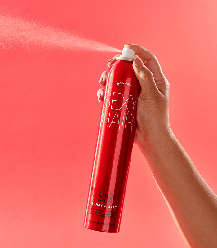 Hand spraying Big Spray & Stay hairspray with visible mist