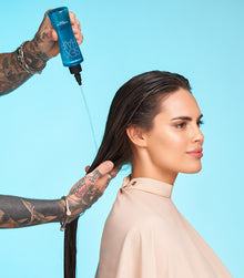 Stylist applying Healthy SexyHair Gloss N' Glow Rinse to model's wet dark hair