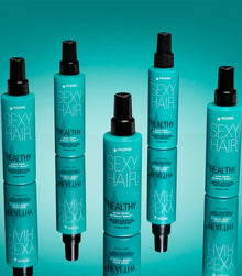 Multiple Healthy SexyHair Shine Show Blowout Spray bottles arranged on teal