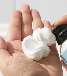 White mousse foam dispensed from Texture SexyHair Foam Party bottle onto palm of hand